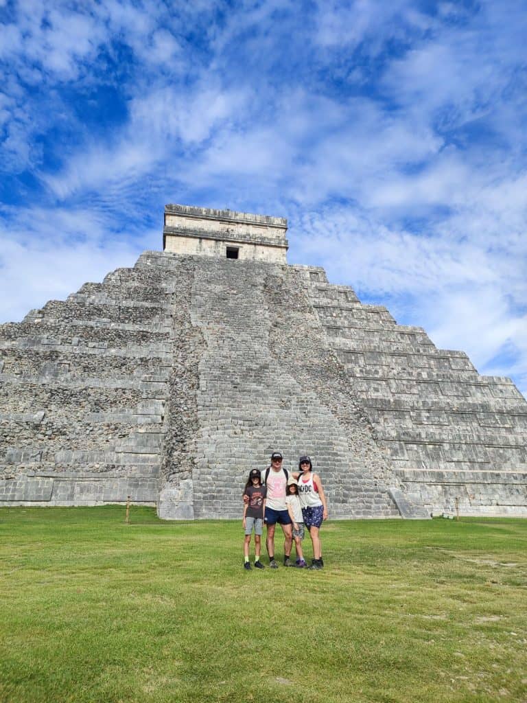 Family of four stand in front of El Castillo pyramid at Chichen Itza