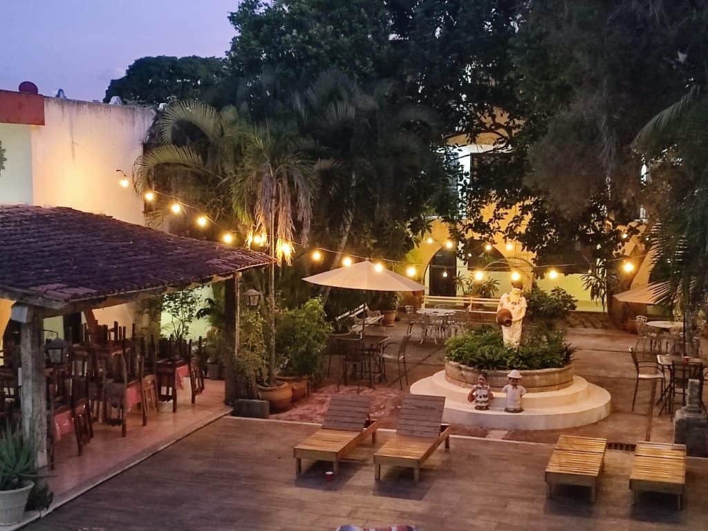 Image taken from above looking down into a hotel courtyard at night. The courtyard has a fountain with a statue in the middle of it and there are string lights stretching across the space