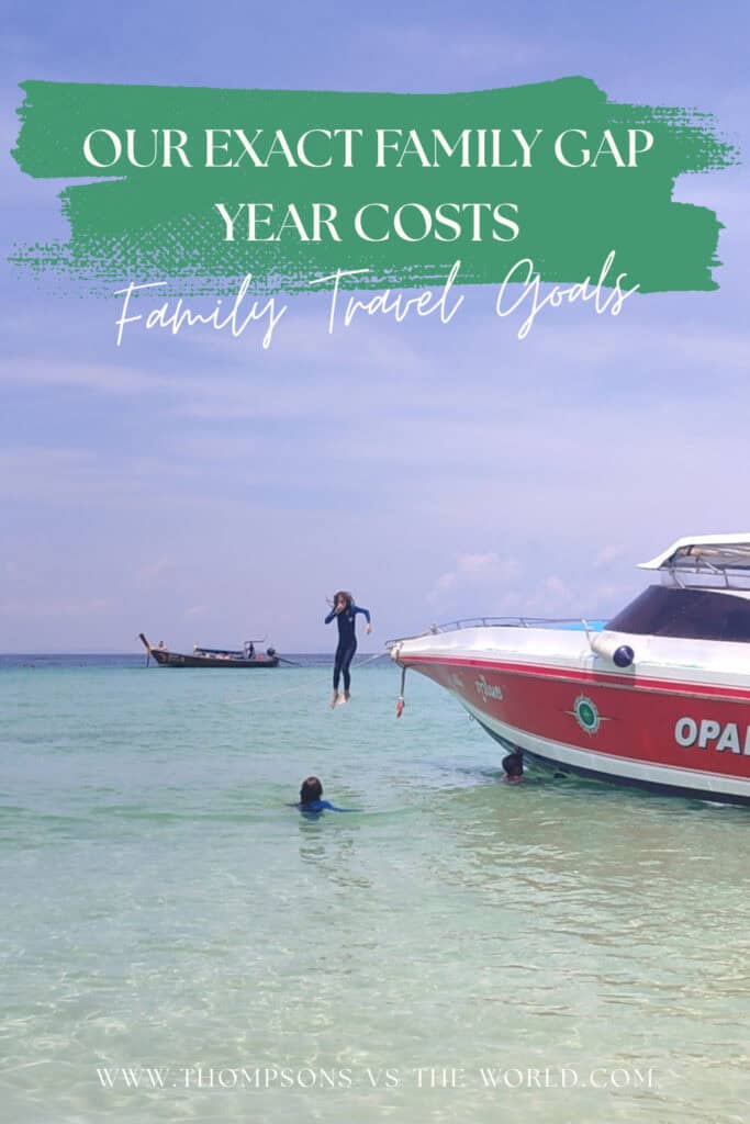 Boy in a blue stinger suit jumps from the front of a boat into clear blue water off the shore of a white sand beach in Thailand. Text overlay reads: 'Our exact family gap year costs: Family Travel Goals'. Save this pin for your planning later!