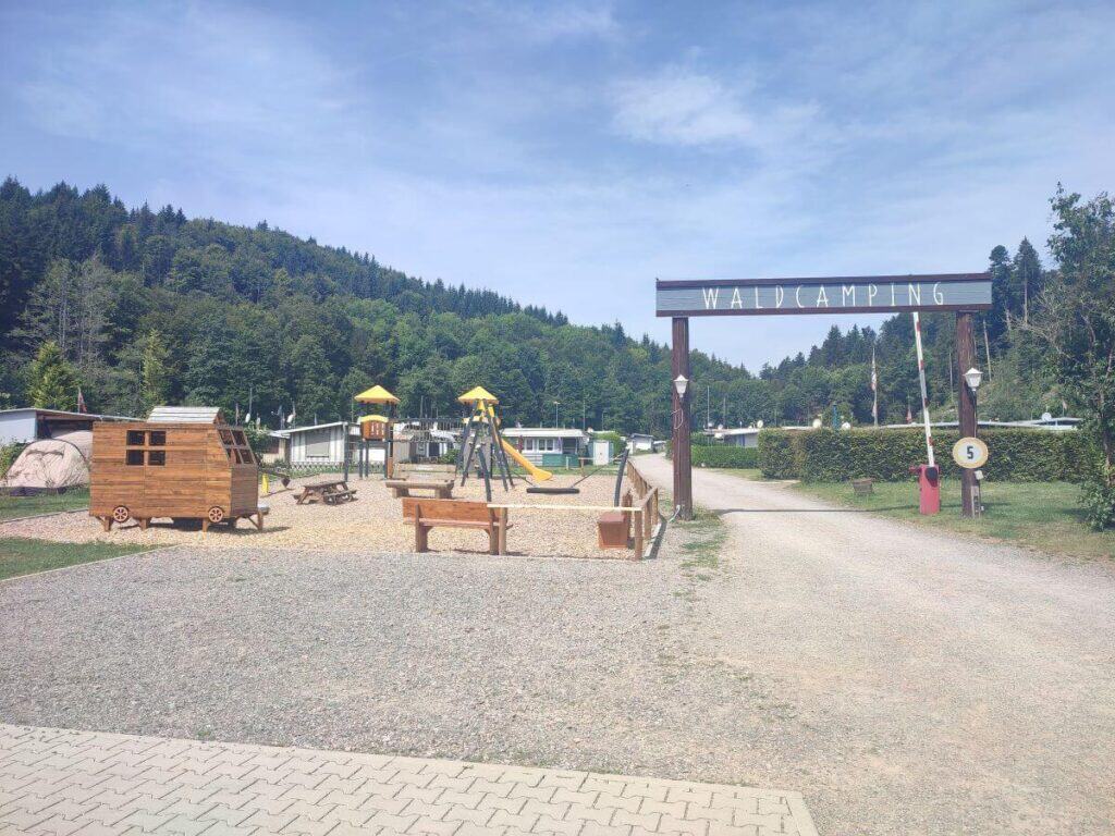 Entrance to Waldcamping Birkendorf - a family campsite in the Black Forest. Image shows a small playground in the foreground and tents/caravans to the rear