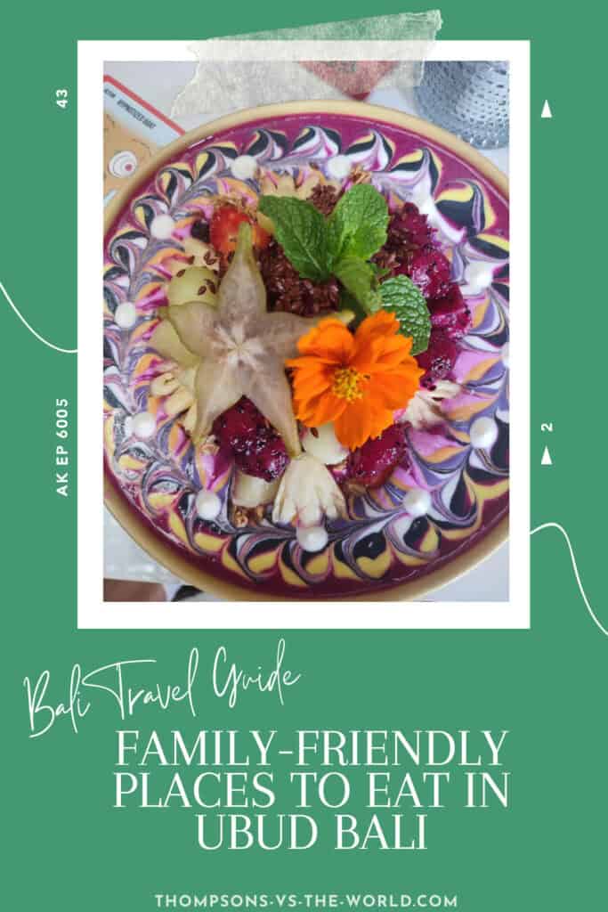 Colourful image featuring a beautifully arranged smoothie bowl, with the yogurt decorated with colourful swirls and stacked with bright fruits and flowers. . Text overlay reads "Bali Travel Guide: Family-Friendly places to eat in Ubud Bali in green and white. Perfect for food lovers planning a trip! Save this pin to your Pinterest board for later reference.