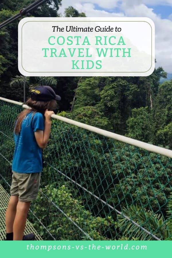 Young boy looks out over the rail into the rainforest canopy beyond, Text overlay reads 'The Ultimate Guide to Costa Rica Travel with Kids'. Pin this for your Costa Rica planning!