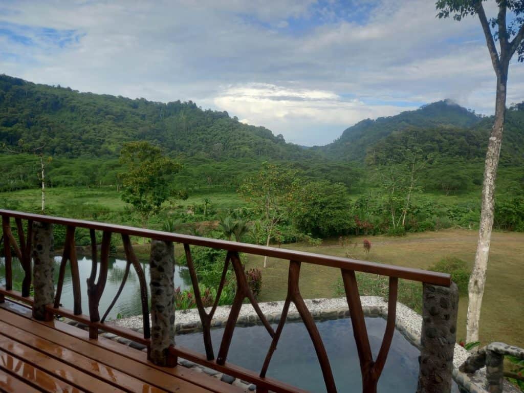 View out from wooden deck over the small natural pool and Costa Rican landscape of hills and jungle beyond.