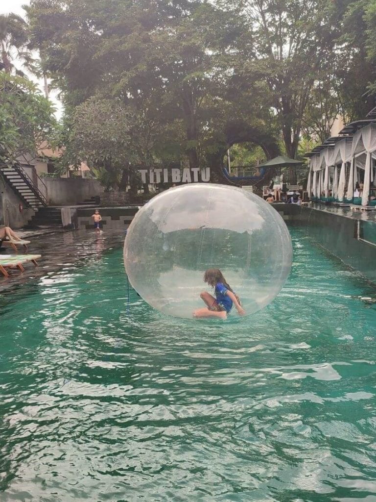 Child rolls in a giant inflatable ball on the surface of the pool at Titi Batu Club in Ubud on a family-friendly Funday Sunday event.
