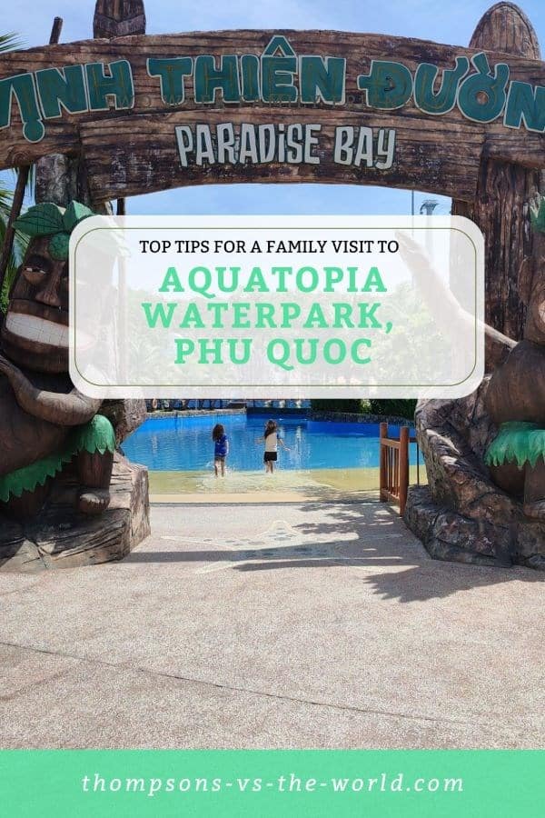 Vibrant image of the entrance to Aquatopia Waterpark at Paradise Bay, Phu Quoc, featuring a wooden sign with lush tropical decorations and two children playing in a shallow pool. Text overlay reads "TOP TIPS FOR A FAMILY VISIT TO AQUATOPIA WATERPARK, PHU QUOC" in green and white. Perfect for families planning a fun waterpark day! Save this pin to your Pinterest board for later reference.