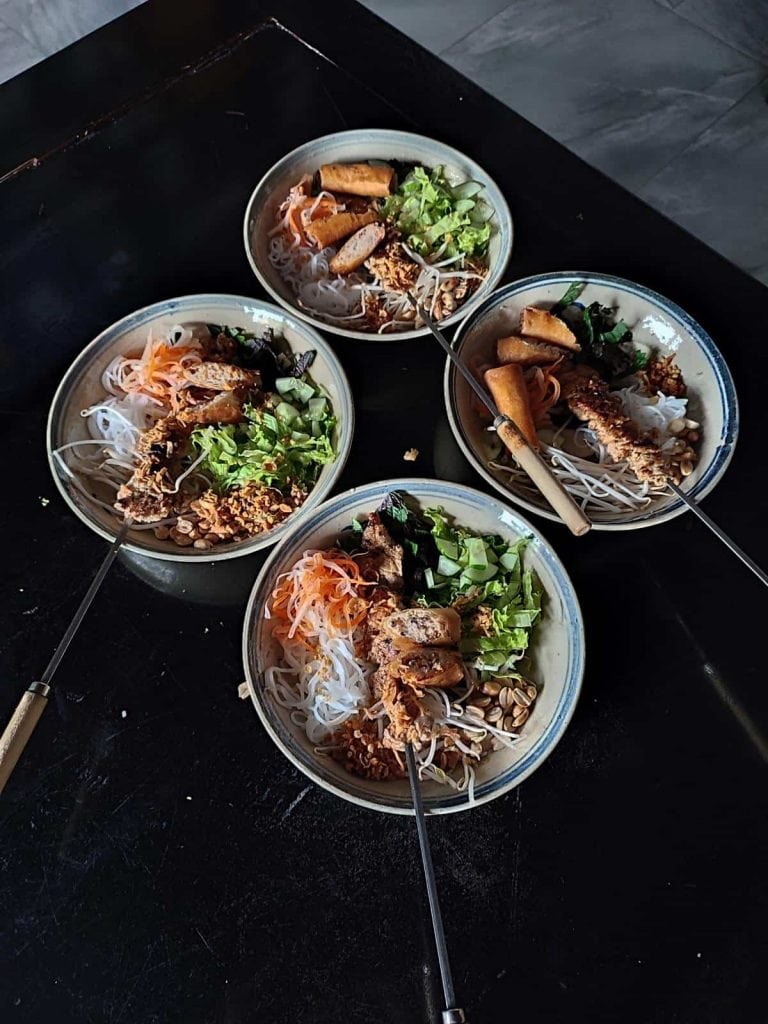 Four dishes of bun thit nuong, a Vietnamese noodle salad, sit on a black countertop. Made during a cooking class with Troc on Phu Quoc Island, Vietnam