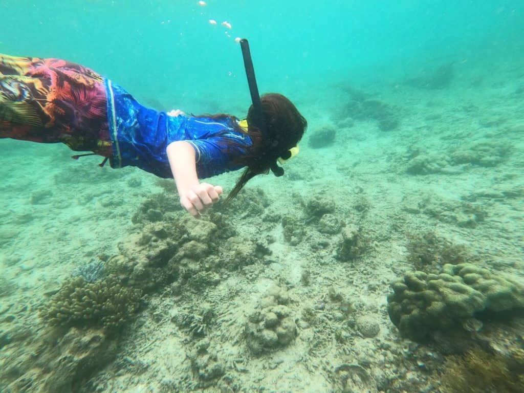 Boy in swimgear and snorkel dives down under the surface of the water to get a closer look at the seabead below in Phu Quoc, Vietnam