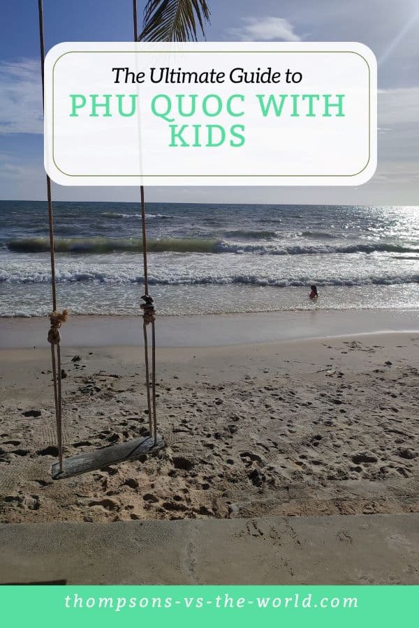A wooden swing hangs in front of a white sand beach with gentle waves rolling in the sea beyond in Phu Quoc, Vietnam. The text overlay reads 'The Ultimate Guide to Phu Quoc with Kids'. Pin this image for your Vietnam planning!