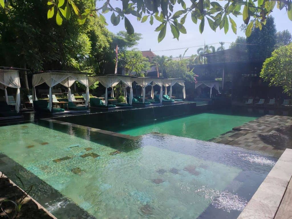 The 25m pool at Titi Batu Ubud with shaded cabanas and lush surroundings.