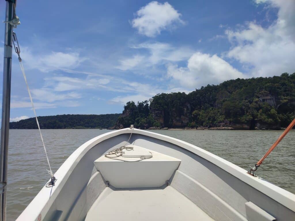 The prow of a small white boat points out across the dark blue water on the way from Kuching to Bako National Park.